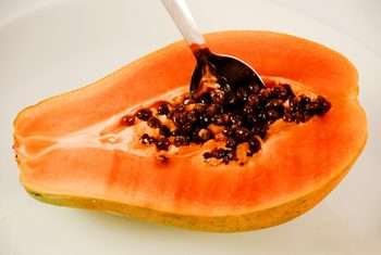 Ripe papaya seeds - Alphanso Afro-Caribbean Foods Spoon stucked in a ripe papaya seeds